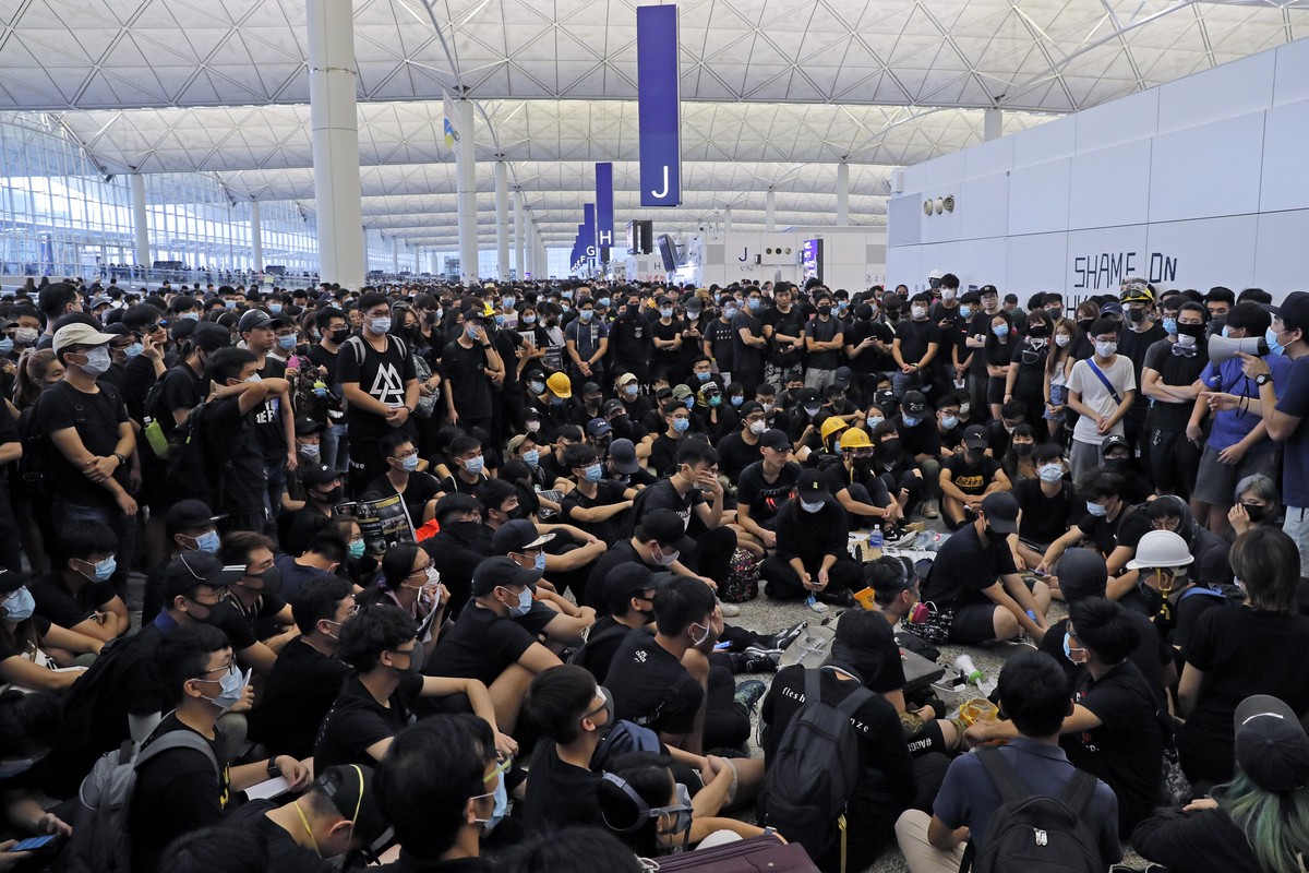 Protesters gather near an information board during a protest at the Hong Kong International Airport, Monday, Aug. 12, 2019. One of the world's busiest airports canceled all flights after thousand ...