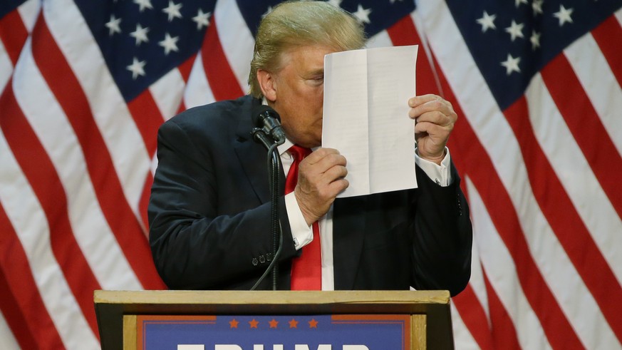 Republican presidential candidate Donald Trump stares at a sheet of talking points and notes as he mocks critics who say he uses prepared speeches or teleprompters during a rally in Eugene, Ore., Frid ...