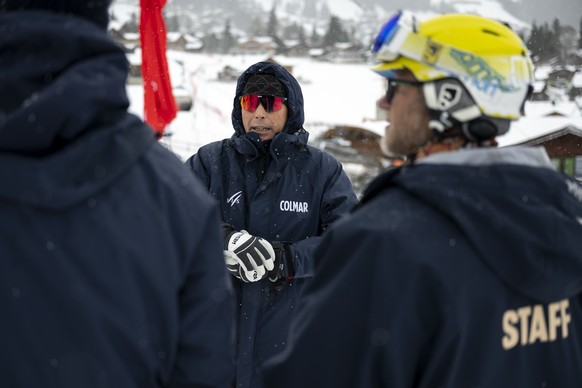 epa12638071 Markus Waldner, FIS Chief Race Director World Cup Men, speaks with staff and FIS personnel next to a member of the civil protection, during the preparation of the race slope near the finis ...