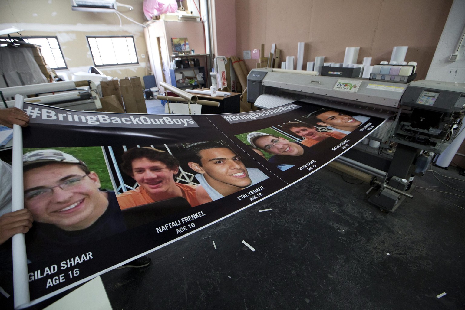 epa04274227 Printing shop owner Jonathan Bracha finishes posters showing the three Israeli missing boys Eyal Yifrah, Gilad Shaar and Naftali Frenkel in his workshop in Jerusalem, Israel, 23 June 2014. ...