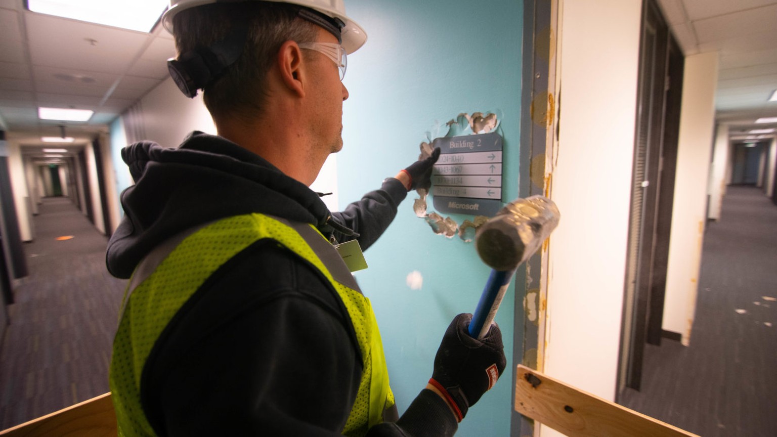 Souvenirjäger bei der Arbeit: Ein Microsoft-Mitarbeiter hämmert ein Hinweisschild in Gebäude 2, das abgerissen wird, aus der Wand.