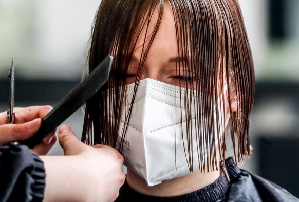 epa09044390 A hairdresser serves her client in a hair salon in Berlin, Germany, 01 March 2021. Hairdressers in Germany were allowed to reopen from 01 March under strict conditions. Hair salons have be ...