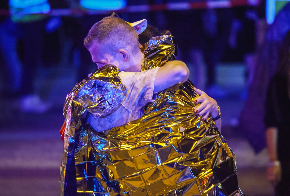 epa13132964 People wrapped in security blankets hug each other near the scene where several people were injured on the sideline of the Christopher Street Day (CSD) parade in Berlin, Germany, 25 July 2 ...