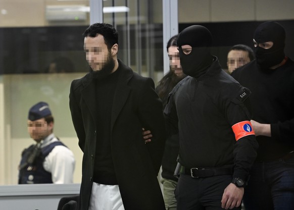 epa10556588 Defendants Salah Abdeslam, Osama Krayem and Mohamed Abrini are escorted by police as they arrive in court during the trial of the 2016 Brussels terror attacks at the Justitia building in B ...