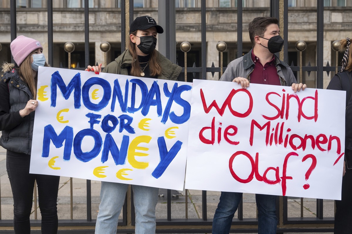 Members of the Junge Union stand in front of the Ministry of Finance holding placards reading "Mondays for Money" and "Where are the millions, Olaf?" in Berlin, Germany, while Olaf ...
