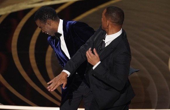 Will Smith, right, hits presenter Chris Rock on stage while presenting the award for best documentary feature at the Oscars on Sunday, March 27, 2022, at the Dolby Theatre in Los Angeles. (AP Photo/Ch ...