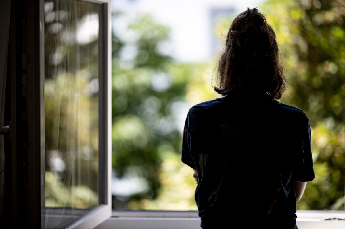 ARCHIV - 13.07.2021, Berlin: ILLUSTRATION - Eine Frau steht in ihrer Wohnung an einem Fenster. (gestellte Szene - zu dpa: