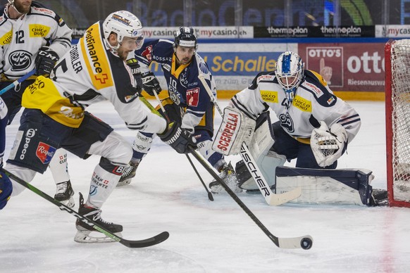 Jerome Bachofner, mitte, von Zug im Spiel gegen Tobias Forler, links, und Torhueter Damiano Ciaccio, links, von Ambri beim Eishockey Meisterschaftsspiel in der Qualifikation der National League zwisch ...