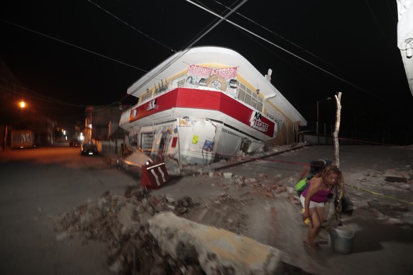 A woman walks past a collapsed building after a 7.1 earthquake, in Jojutla, Morelos state, Mexico, Tuesday, Sept. 19, 2017. The earthquake stunned central Mexico, killing more than 100 people as build ...