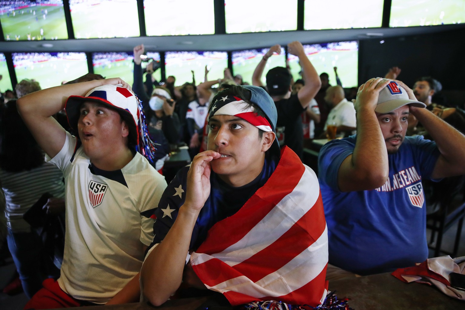 epa10337653 US fans (L-R) Jesus Roman, Nolan Luevano and Erik Hernandez react as Iran and the USA face off in the FIFA World Cup 2022 group B soccer match, at Tom?s Watch Bar in Los Angeles, Californi ...