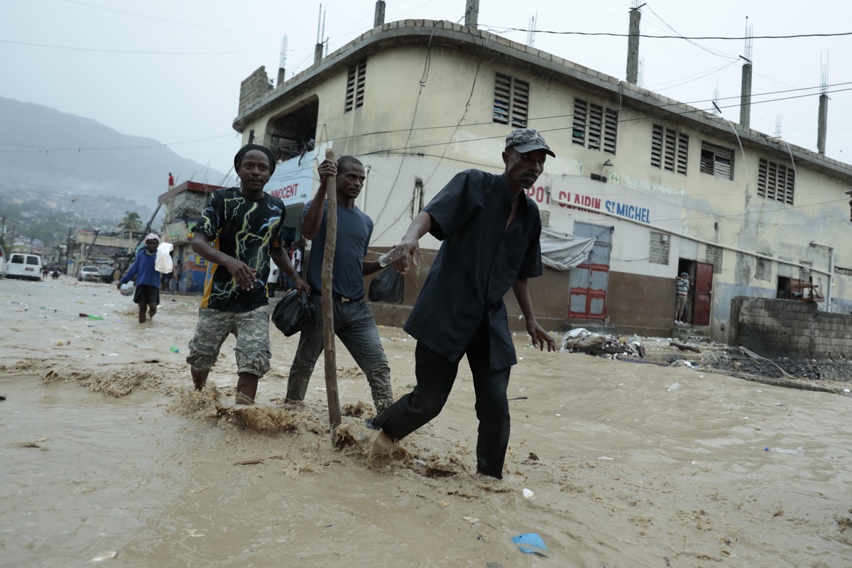 Residents wade through a flooded street after a heavy rain in Port-au-Prince, Haiti, Saturday, June 3, 2023. (AP Photo/Odelyn Joseph)