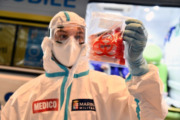 epa08818085 A health worker collects swab samples for a polymerase chain reaction (PCR) test at the drive through coronavirus testing facility set up at the Genoa Fair during the coronavirus disease C ...