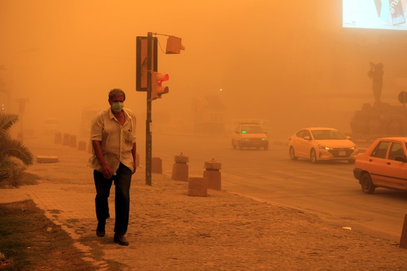 epa09968266 An Iraqi man wears a face mask as he walk at the Kahraman square shrouded in heavy dust in central Baghdad, Iraq, 23 May 2022. The dust storm sent hundreds of people with respiratory probl ...