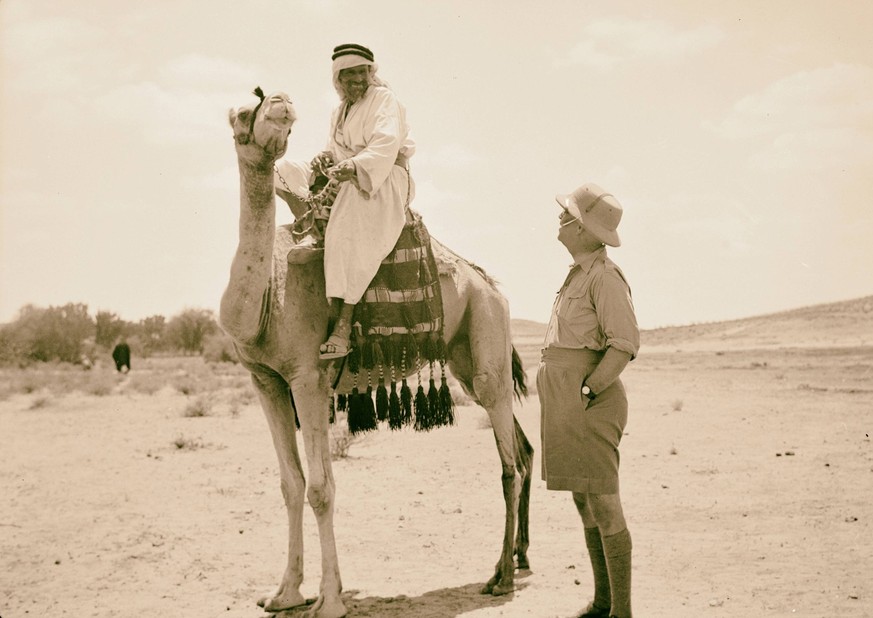 The Dept. of Health, Mobile Ophthalmic Clinic Operating in Arab villages of the South Country, N.E. of Gaza. Dr. V. L. Ferguson talking to a camel man of the desert mounted on his riding camel. 1939,  ...
