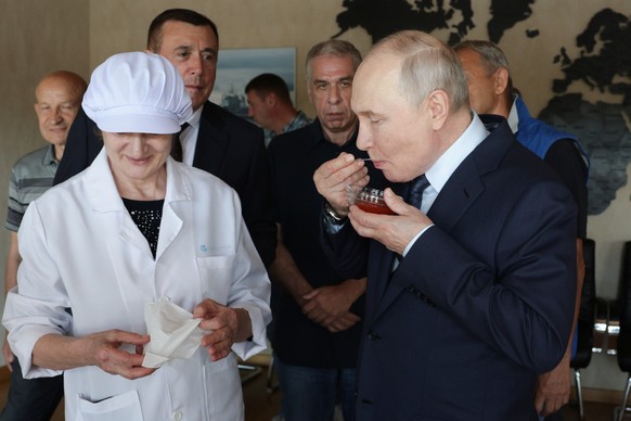 Russian President Vladimir Putin, right, tastes products as he visits the Yasny fish processing complex at Kitovoye village on the Iturup Island, the largest of the Kuril Islands of Russia's fare ...
