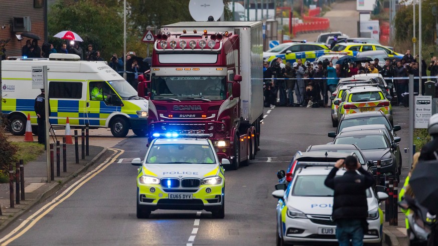 epa07943575 Police drive the lorry container along the road from the scene in Waterglade Industrial Park in Grays, Essex, Britain, 23 October 2019. A total of 39 bodies were discovered inside a lorry  ...