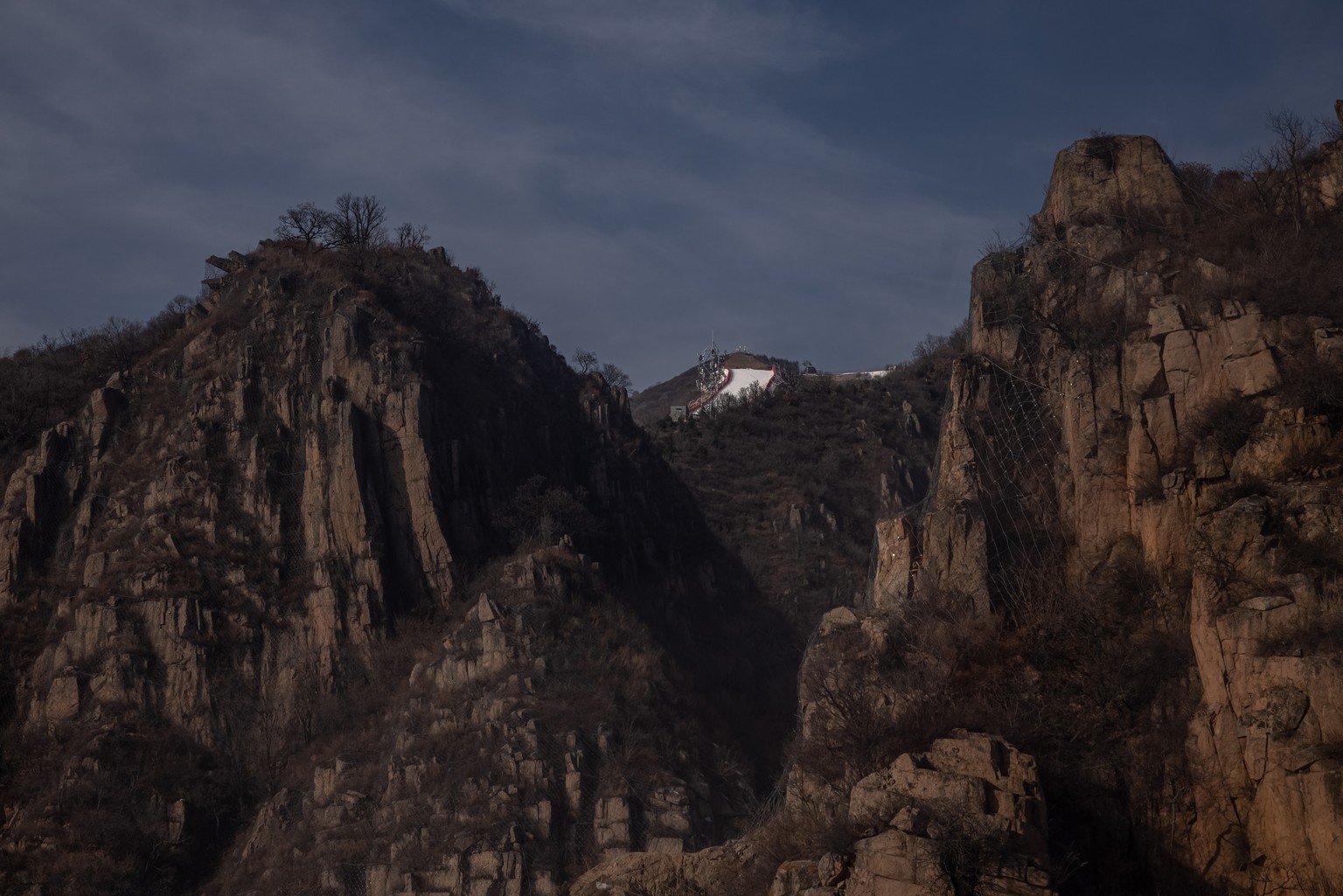 epa09718018 A ski slope at Yanqing National Alpine Skiing Center, the Olympic venue for alpine skiing, is seen behind snowless mountains, in Beijing, China, 30 January 2022. The Beijing 2022 Winter Ol ...