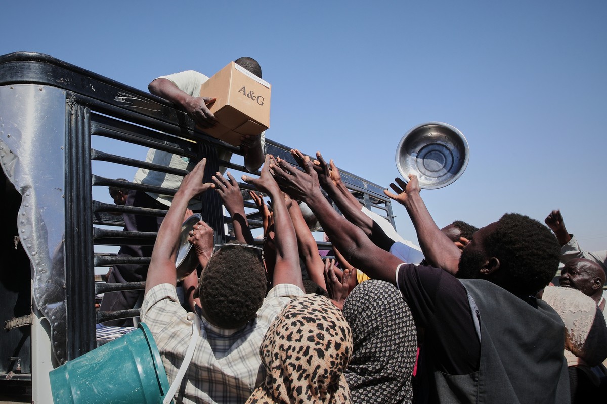 FILE - Sudanese families displaced from El-Fasher reach out as aid workers distribute food supplies at the newly established El-Afadh camp in Al Dabbah, Sudan's Northern State, Nov. 16, 2025. (AP ...