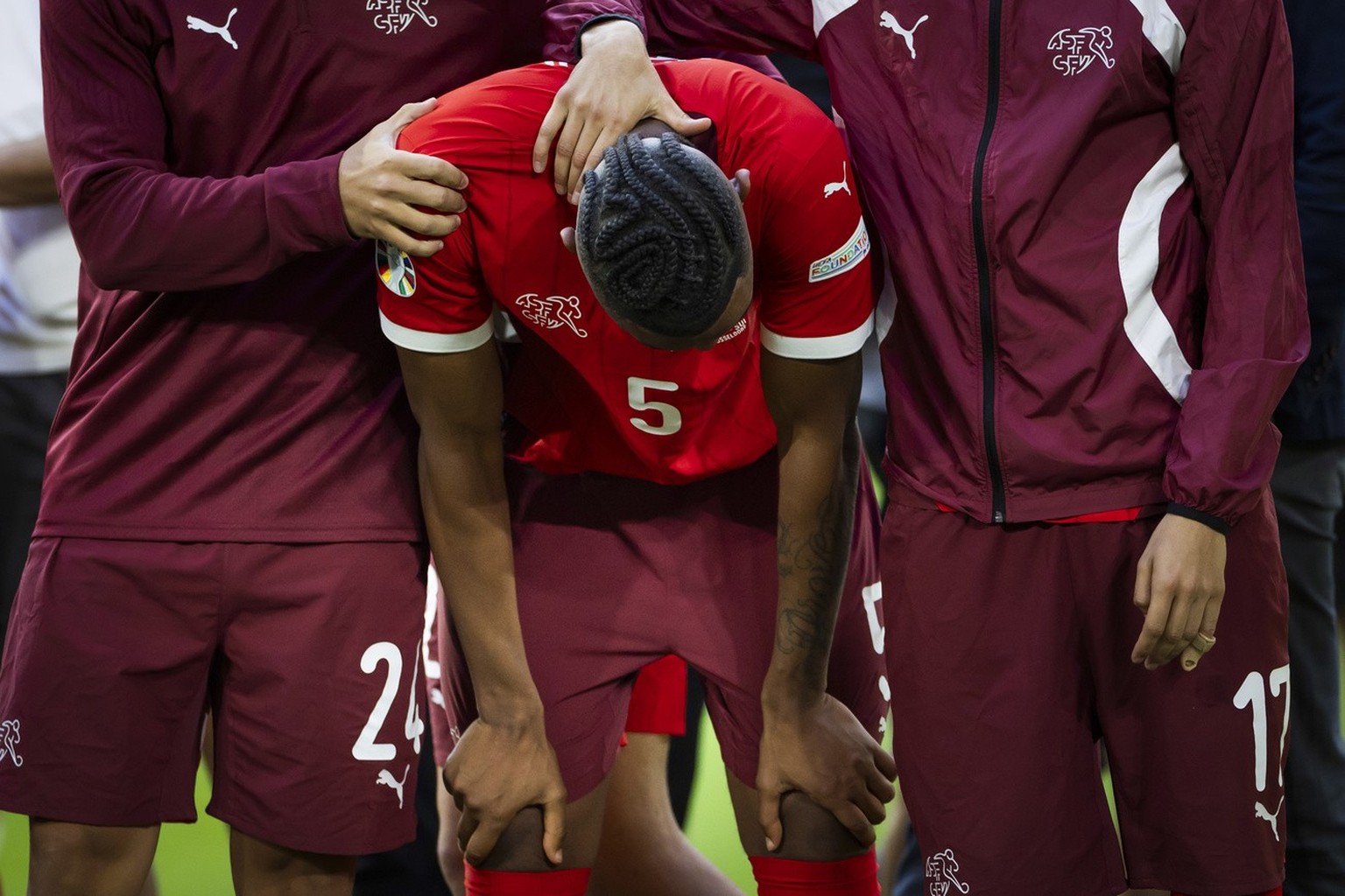 Switzerland&#039;s Manuel Akanji, center, reacts between his teammates Ardon Jashari, left, and Ruben Vargas after losing the penalty shoot-out of the quarter final match between England and Switzerla ...