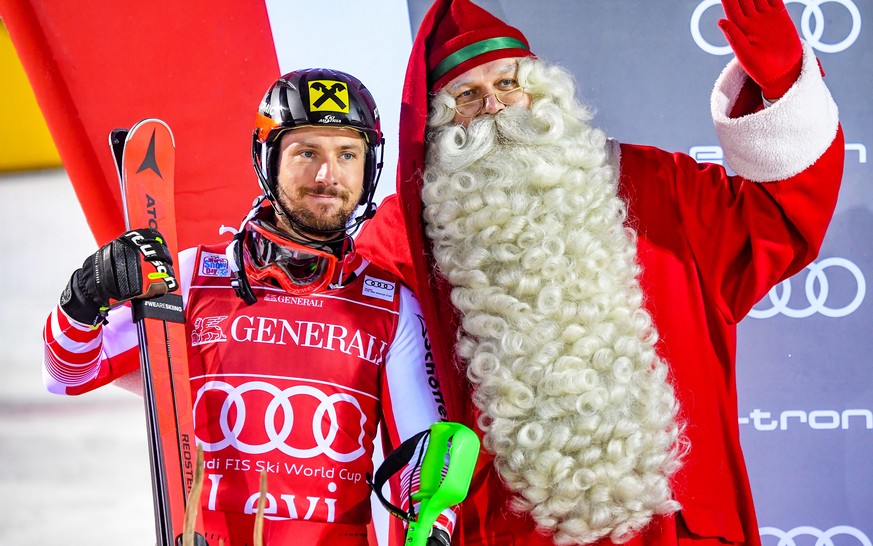 epa07175170 Marcel Hirscher (L) of Austria poses with Santa Claus on the podium after winning the men&#039;s Slalom race of the Alpine Skiing World Cup in Levi, Finland, 18 November 2018. EPA/KIMMO BR ...