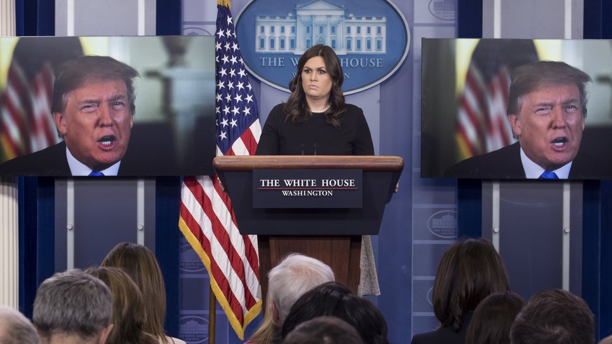 epaselect epa06417197 White House Press Secretary Sarah Huckabee Sanders stands beside monitors showing US President Donald J. Trump delivering a statement on the economy, at the beginning of a news c ...