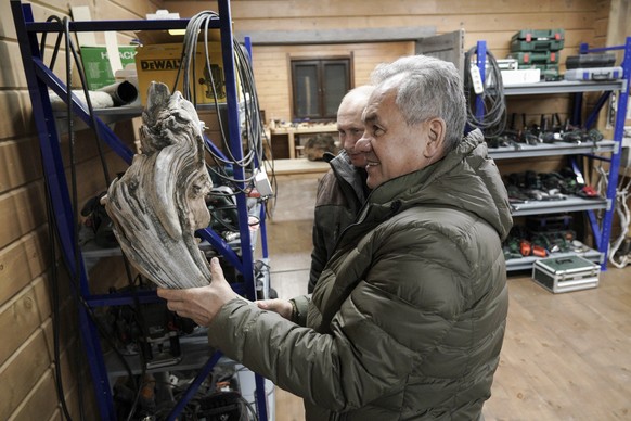 In this photo made available on Sunday, March 21, 2021, Russia Defense Minister Sergei Shoigu, foreground, and Russian President Vladimir Putin look at a piece wood for crafting at Sergei Shoigu&#039; ...