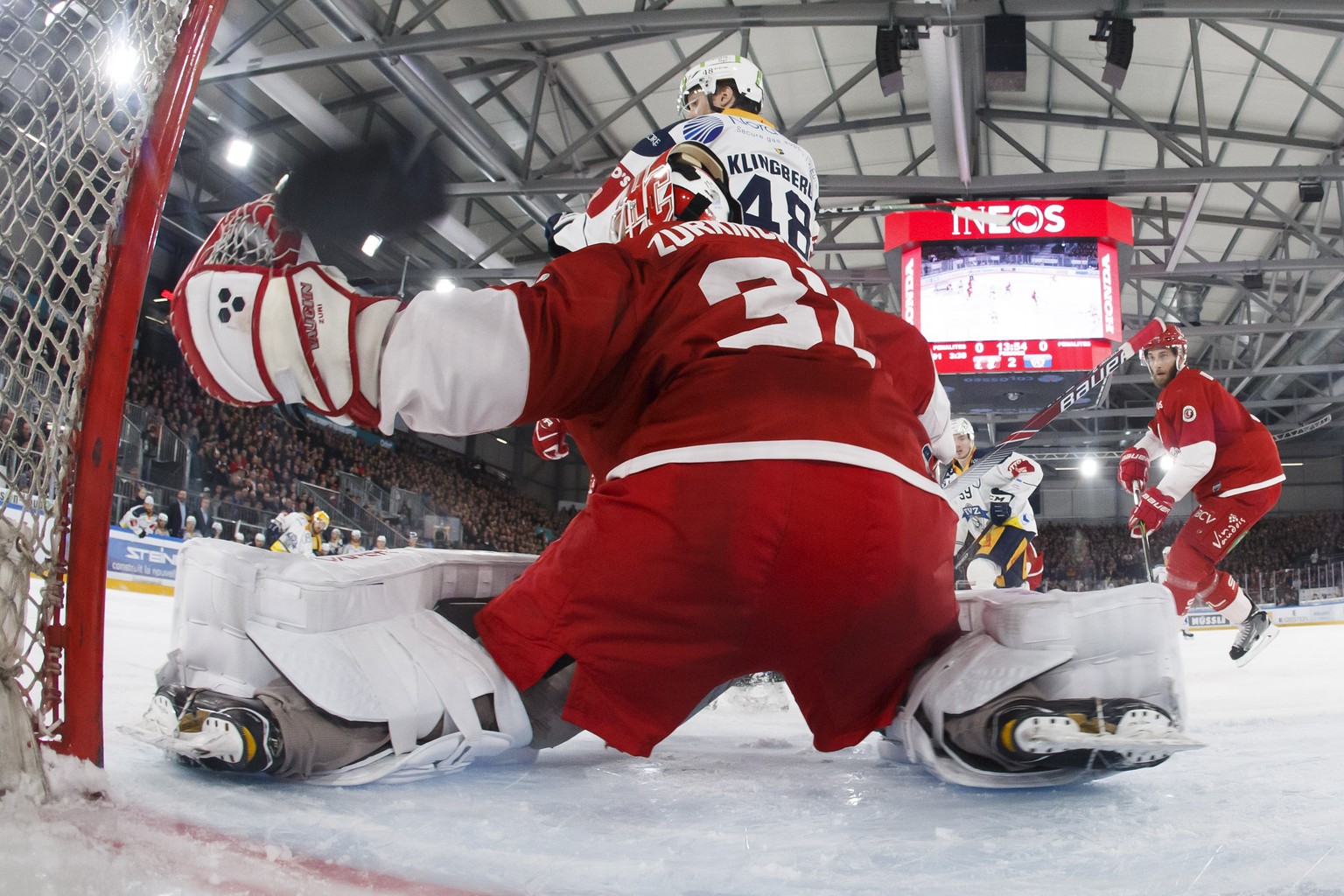 Zug&#039;s center Garrett Roe, of USA, left, scores the 0:1 against Lausanne&#039;s goaltender Sandro Zurkirchen #31past Zug&#039;s forward Carl Klingberg #48, of Sweden, during the third leg of the p ...