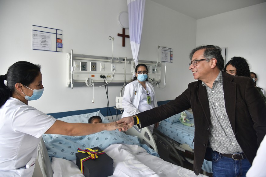 In this handout photo released by Colombian Presidential Press Office, Colombia&#039;s President Gustavo Petro greets a nurse tending to one of the four Indigenous children who survived an Amazon plan ...