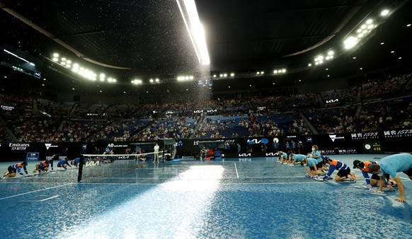 Staff dry the court after a rain shower during the quarterfinal match between Stefanos Tsitsipas of Greece and Jannik Sinner of Italy on Rod Laver Arena at the Australian Open tennis championships in  ...