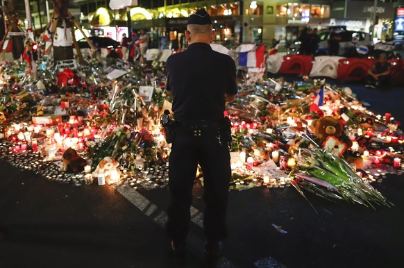 epaselect epa05428721 A police officer stands in front of flowers and candles on the &#039;Promenade des Anglais&#039; where the truck crashed into the crowd during the Bastille Day celebrations, in N ...
