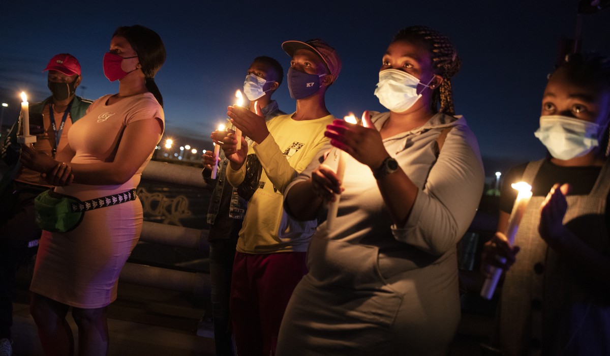 epa08913273 Members of the public stand with candles during a memorial for victims of the Covid-19 Coronavirus on New Year's eve who have died in the city during 2020, Johannesburg, South Africa, ...