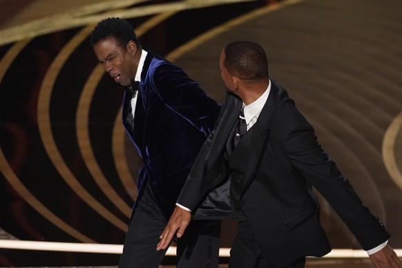 Will Smith, right, hits presenter Chris Rock on stage while presenting the award for best documentary feature at the Oscars on Sunday, March 27, 2022, at the Dolby Theatre in Los Angeles. (AP Photo/Ch ...