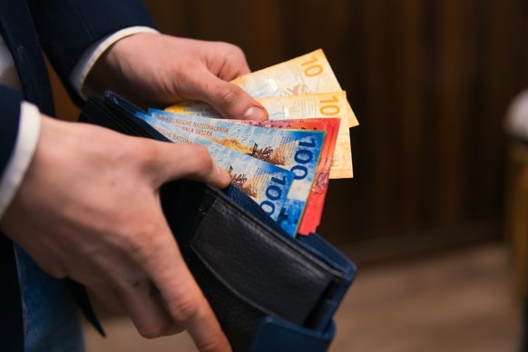 formell gekleideter Mann zählt Schweizer Franken-Banknoten. Konzept für Wirtschaft, Investitionen und Finanzen in der Schweiz