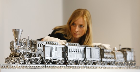 A Christie&#039;s employee poses with &#039;Jim Beam-J.B.Turner Train stainless steel and bourbon&#039; by Jeff Koons on display at the auction rooms in London, Friday, April 11, 2014. The artwork val ...