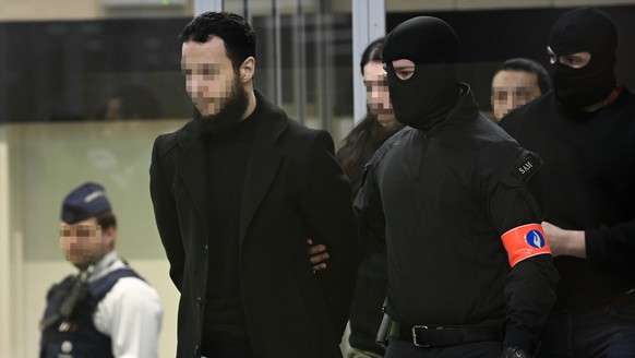 epa10556588 Defendants Salah Abdeslam, Osama Krayem and Mohamed Abrini are escorted by police as they arrive in court during the trial of the 2016 Brussels terror attacks at the Justitia building in B ...