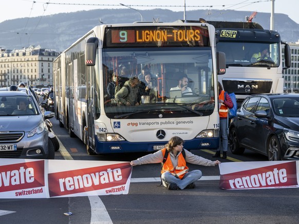 epa09889345 A climate activist sits down on the road during the &#039;Renovate Switzerland&#039; roadblock protest action at the Mont-Blanc bridge, in Geneva, Switzerland, 14 April 2022. The protest w ...