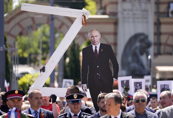 People hold a picture of Russian President Vladimir Putin and a letter Z, during the Victory Day ceremony in Belgrade, Serbia, Monday, May 9, 2022. People marking the 77th anniversary of the victory o ...