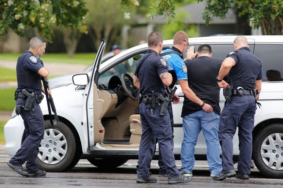 Law enforcement officers do a security check on a man in a vehicle near the site of a shooting of police in Baton Rouge, Louisiana, United States, July 17, 2016. REUTERS/Joe Penney