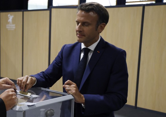 French President Emmanuel Macron casts his vote followed by his wife Brigitte Macron in the first round of French parliamentary election at a polling station in Le Touquet, northern France, Sunday Jun ...