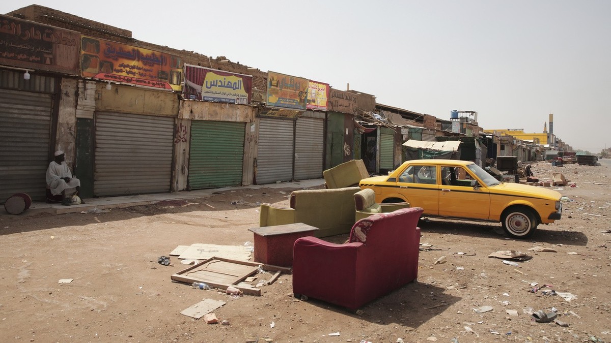 A man sits by shuttered shops in Khartoum, Sudan, Monday, April 16, 2023. Sudan's embattled capital has awoken to a third day of heavy fighting between the army and a powerful rival force for con ...
