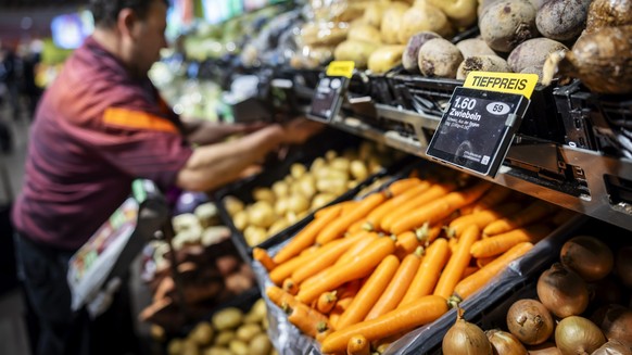 Ein Mitarbeiter raeumt Gemuese ein, neben einem Schild mit der Aufschrift "Tiefpreis" in der Migros Limmatplatz, aufgenommen anlaesslich einer Medienkonferenz zu Neuerungen in den Migros-Sup ...