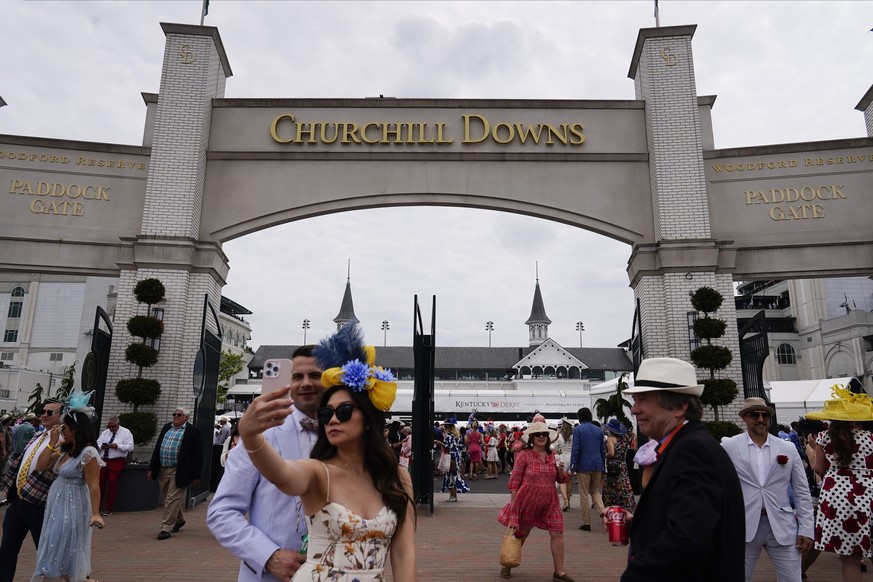 People walk on the grounds of Churchill Downs before the 149th running of the Kentucky Derby horse race Saturday, May 6, 2023, in Louisville, Ky. (AP Photo/Brynn Anderson)