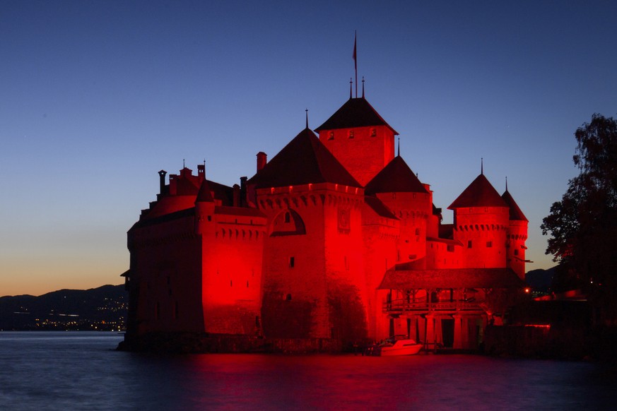 epaselect epa08502852 The Chillon Castle is lit up in red on the shore of Lake Geneva during the'Night of Light campaign, in Veytaux near Montreux, Switzerland, 22 June 2020. Monday evening numer ...