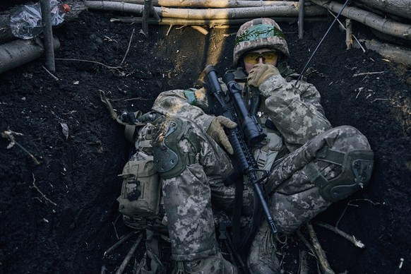 A Ukrainian soldier sits in a trench near Russian positions near Bakhmut, Donetsk region, Ukraine, Sunday, March 5, 2023. (AP Photo/Libkos)