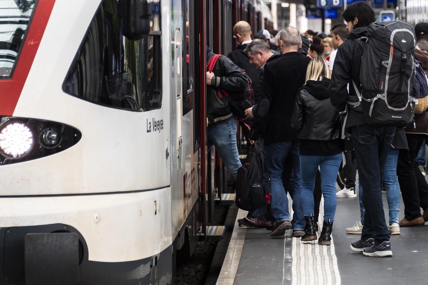 Commuters board on a train at the CFF/SBB station during the spread of the pandemic Coronavirus (COVID-19) disease in Lausanne, Switzerland, Monday, May 11, 2020. In Switzerland from today, the Swiss  ...