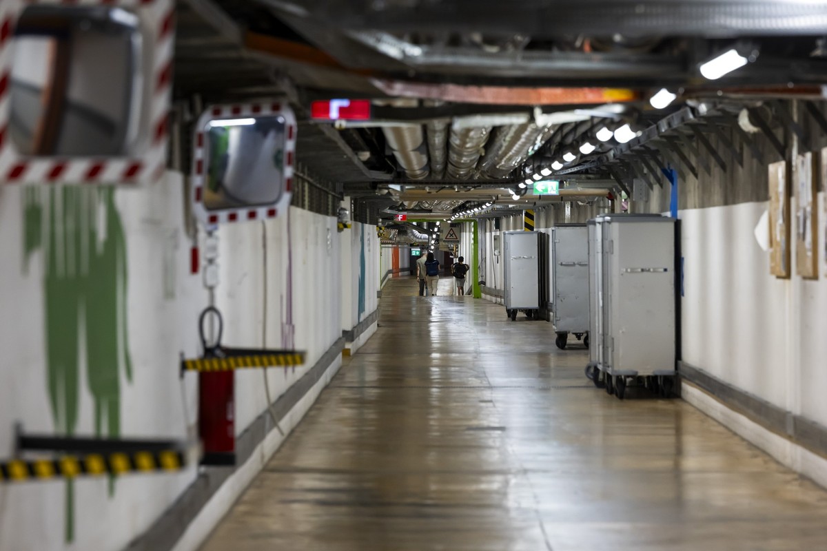 Des personnes marchent dans l'un des tunnels souterrains des Hopitaux Universitaires de Geneve (HUG) reliant les differents batiments des HUG, ce mercredi 13 aout 2025 a Geneve. (KEYSTONE/Salvato ...