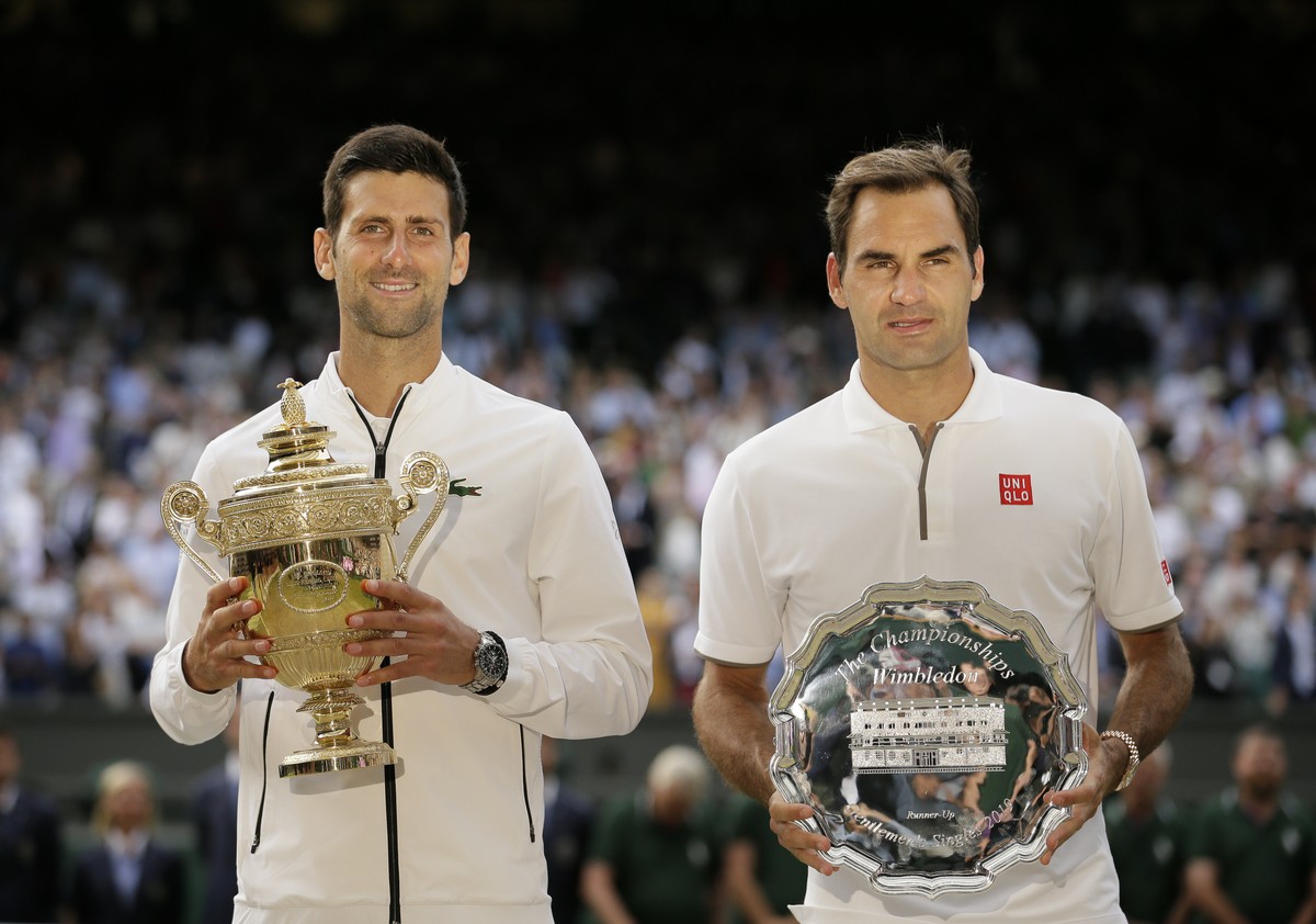 FILE - Serbia's Novak Djokovic, left, and Switzerland's Roger Federer pose with the trophies after the men's singles final match of the Wimbledon Tennis Championships in London, Sunday, ...