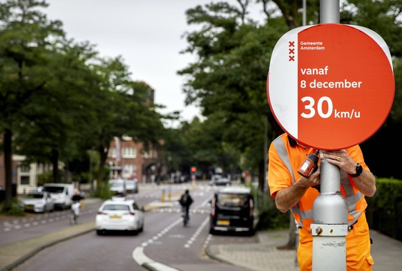 AMSTERDAM - A municipal employee places a speed sign. Amsterdam is preparing to introduce the speed limit of 30 kilometers per hour. The measure will come into effect in December, but new speed signs  ...