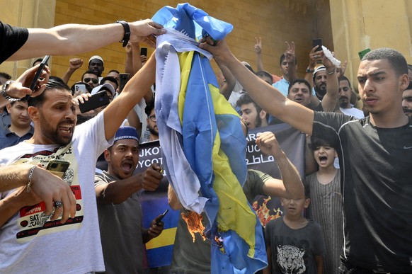 epa10731906 Lebanese protesters burn Swedish and Israeli flags as they attend a protest against the burning of a copy of the Koran in Sweden, after Friday noon prayers outside Muhammad al-Amin Mosque  ...
