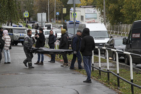 Funeral workers carry a body of victim at the scene of a shooting at school No. 88 in Izhevsk, Russia, Monday, Sept. 26, 2022. Authorities say a gunman has killed 15 people and wounded 24 others in a  ...